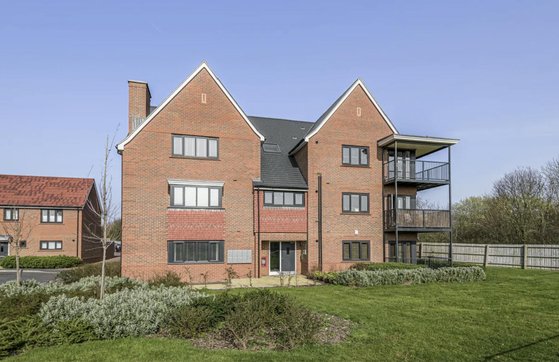 Large brick building against a blue sky, with a steel balcony on the right hand side.